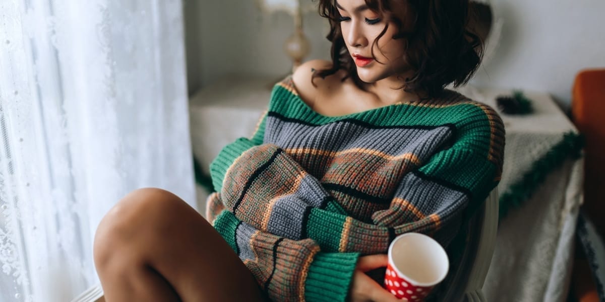 Pulovere din lână și cașmir împăturite pe un fundal cald, comparație de materiale pentru iarnă